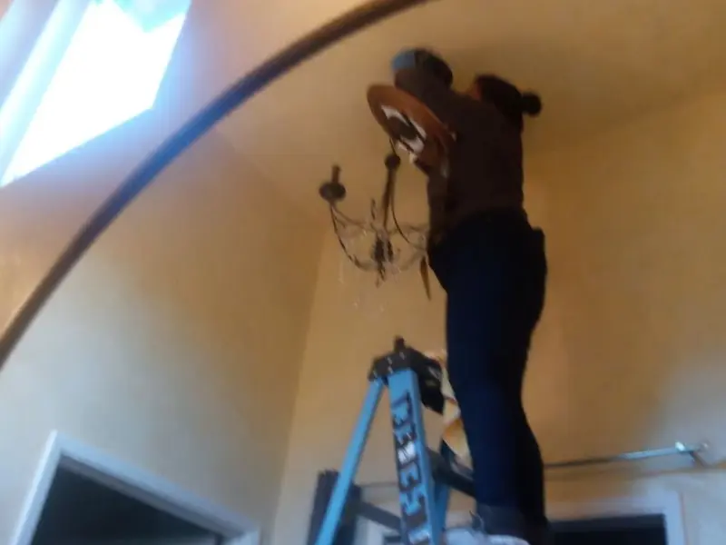 Electrician installing a chandelier in a West Slope residence